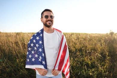 Photo of Happy man with flag of USA outdoors. Space for text