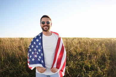 Photo of Happy man with flag of USA outdoors. Space for text