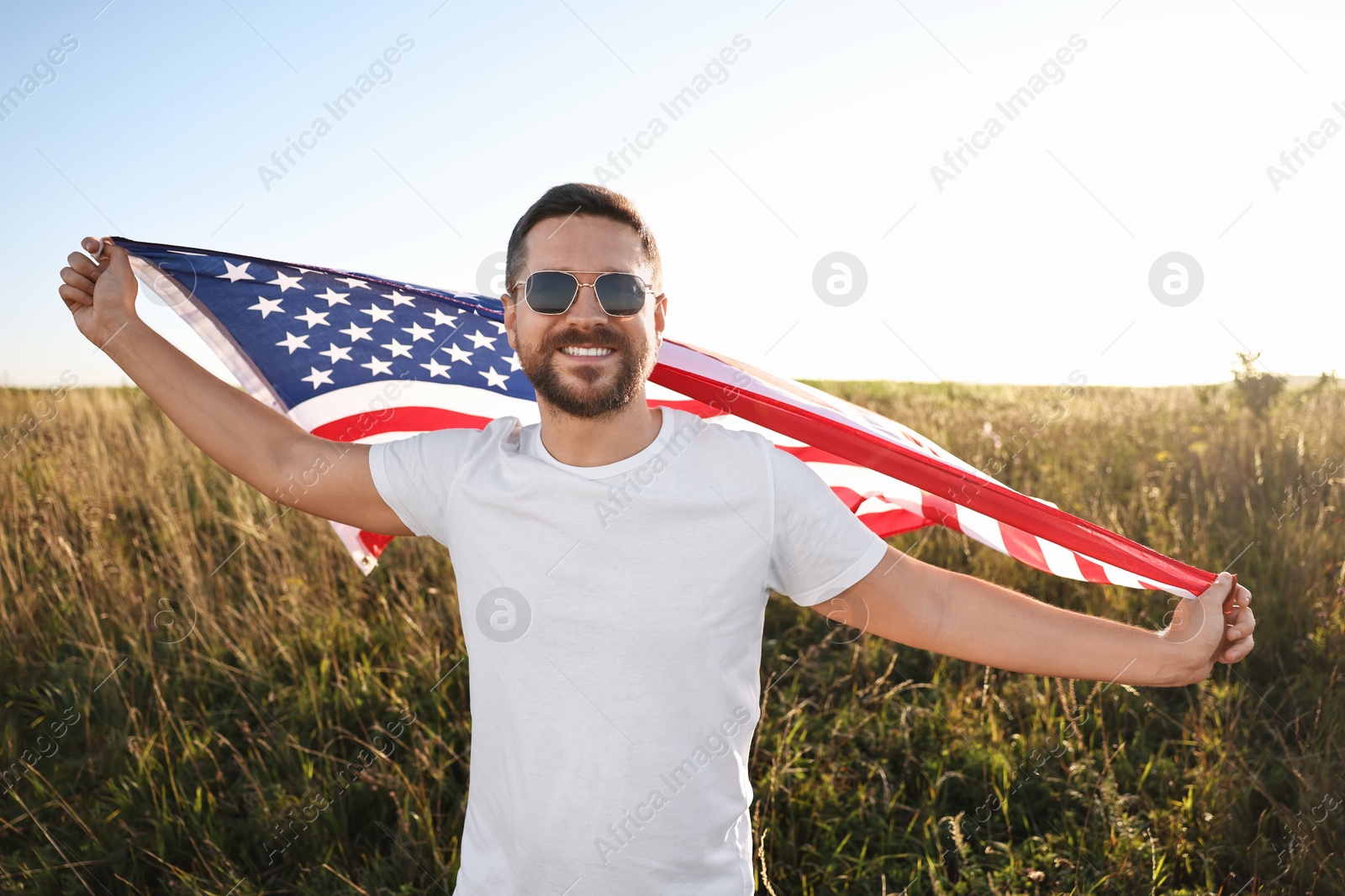 Photo of Happy man with flag of USA outdoors