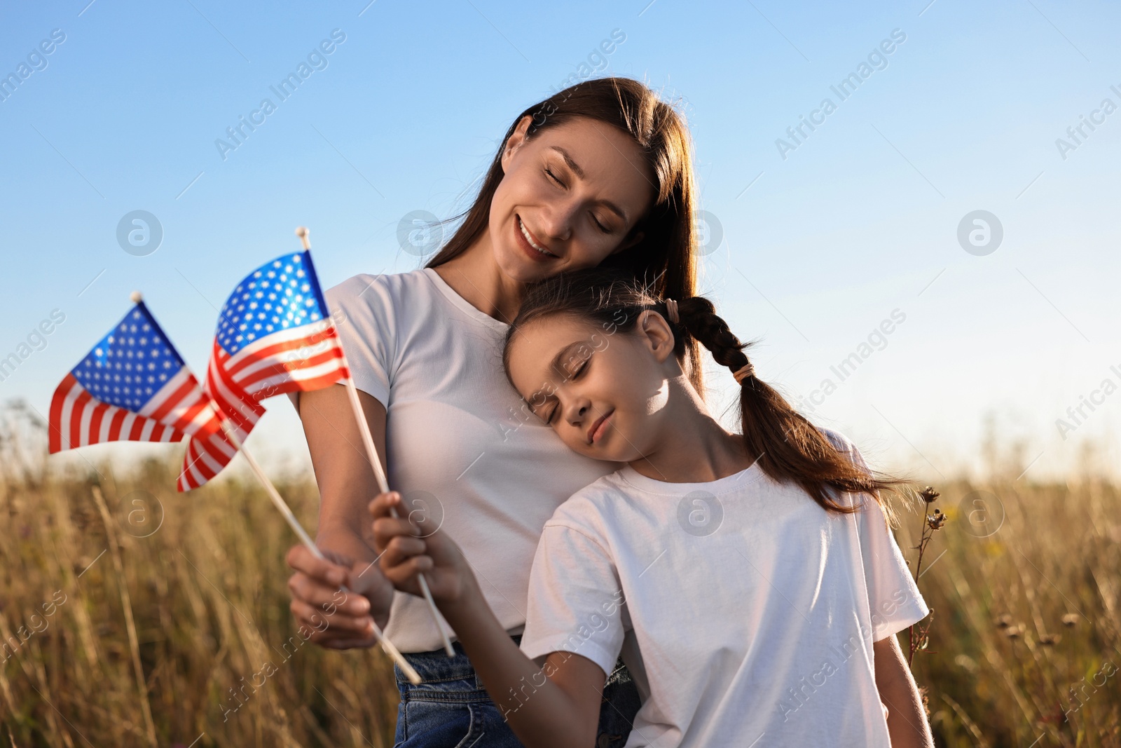 Photo of Happy mother and daughter with flags of USA outdoors