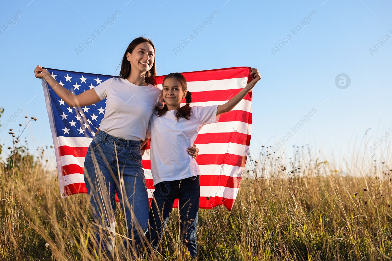 Photo of Happy mother and daughter with flag of USA outdoors. Space for text