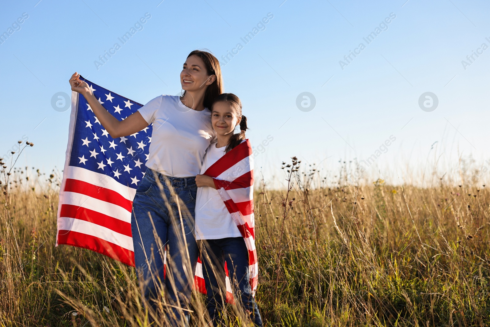 Photo of Happy mother and daughter with flag of USA outdoors. Space for text