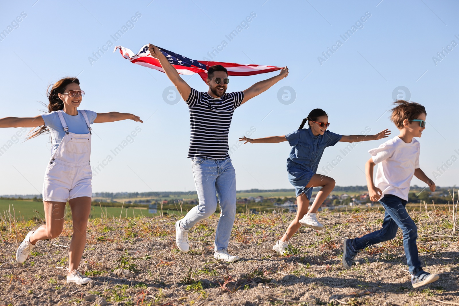 Photo of Happy family running with flag of USA outdoors