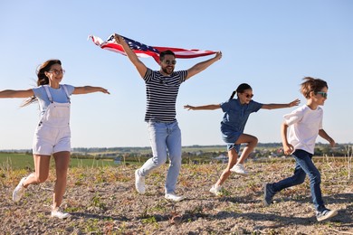 Happy family running with flag of USA outdoors