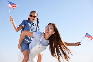 Happy mother and daughter with flags of USA outdoors