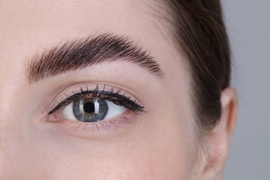 Photo of Woman after brow lamination procedure on grey background, closeup