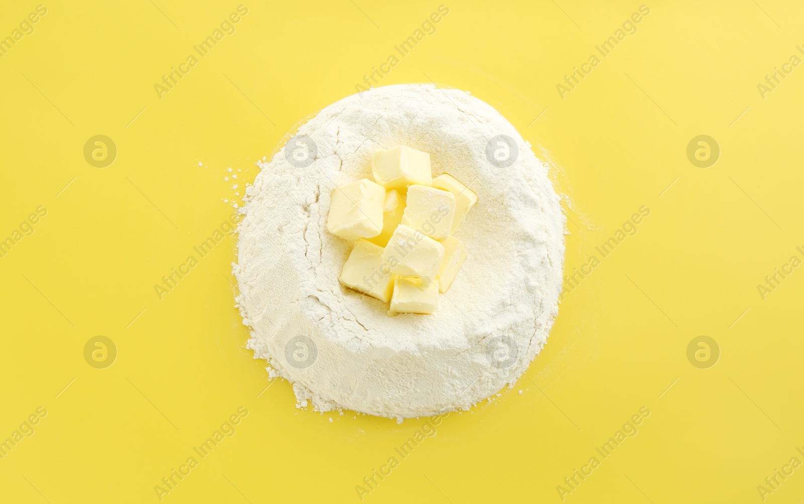 Photo of Cooking homemade pie. Flour with butter on yellow background, top view