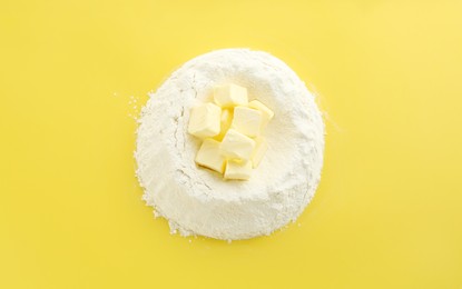 Photo of Cooking homemade pie. Flour with butter on yellow background, top view