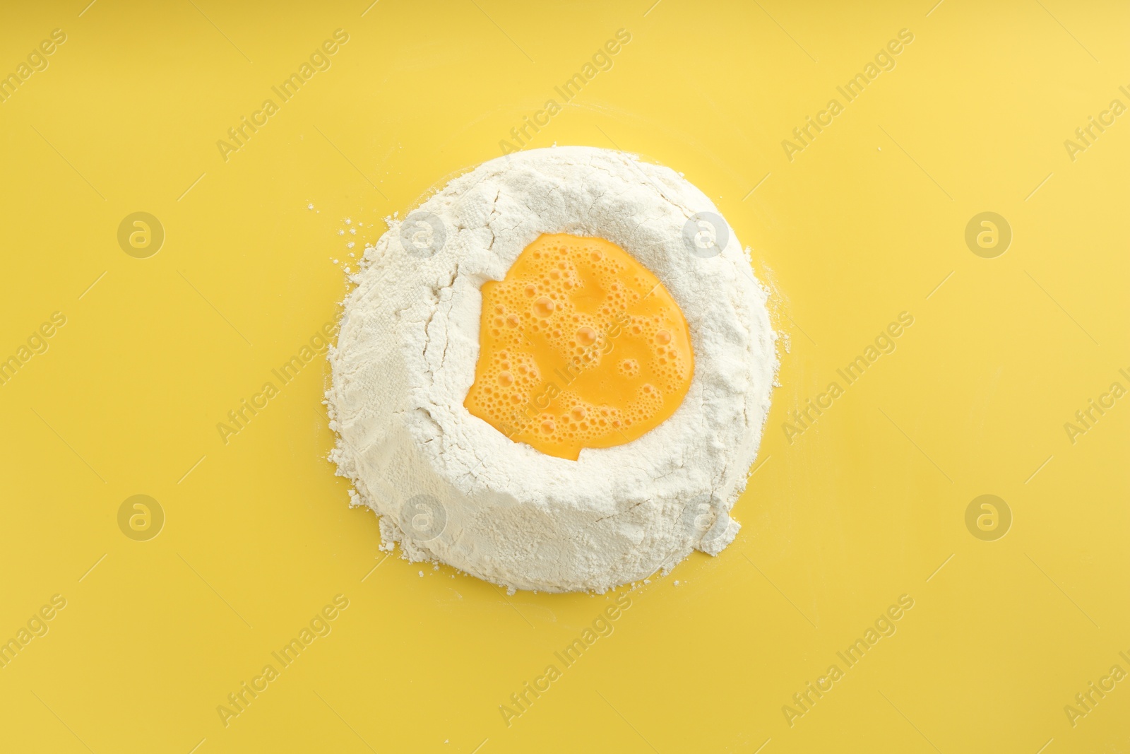 Photo of Cooking homemade pie. Flour with eggs on yellow background, top view