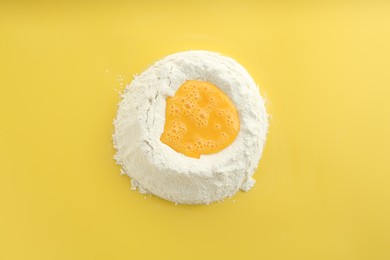 Photo of Cooking homemade pie. Flour with eggs on yellow background, top view