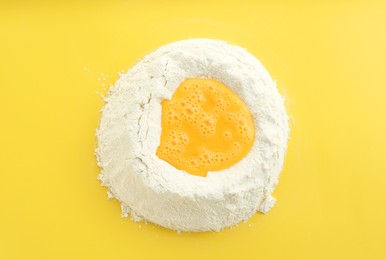 Photo of Cooking homemade pie. Flour with eggs on yellow background, top view