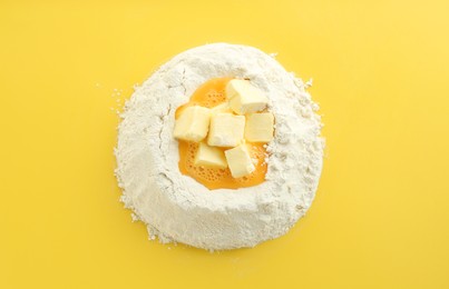 Photo of Cooking homemade pie. Flour with eggs and butter on yellow background, top view