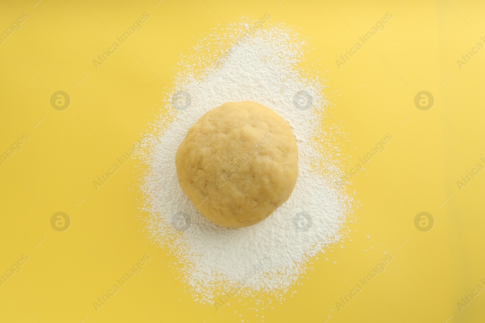 Photo of Cooking homemade pie. Raw dough and flour on yellow background, top view