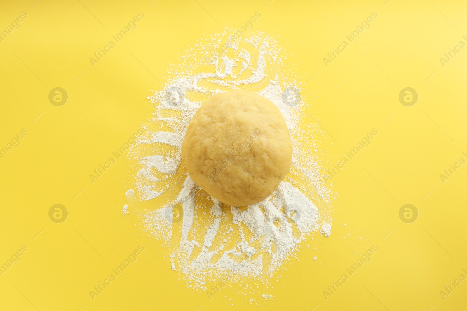 Photo of Cooking homemade pie. Raw dough and flour on yellow background, top view