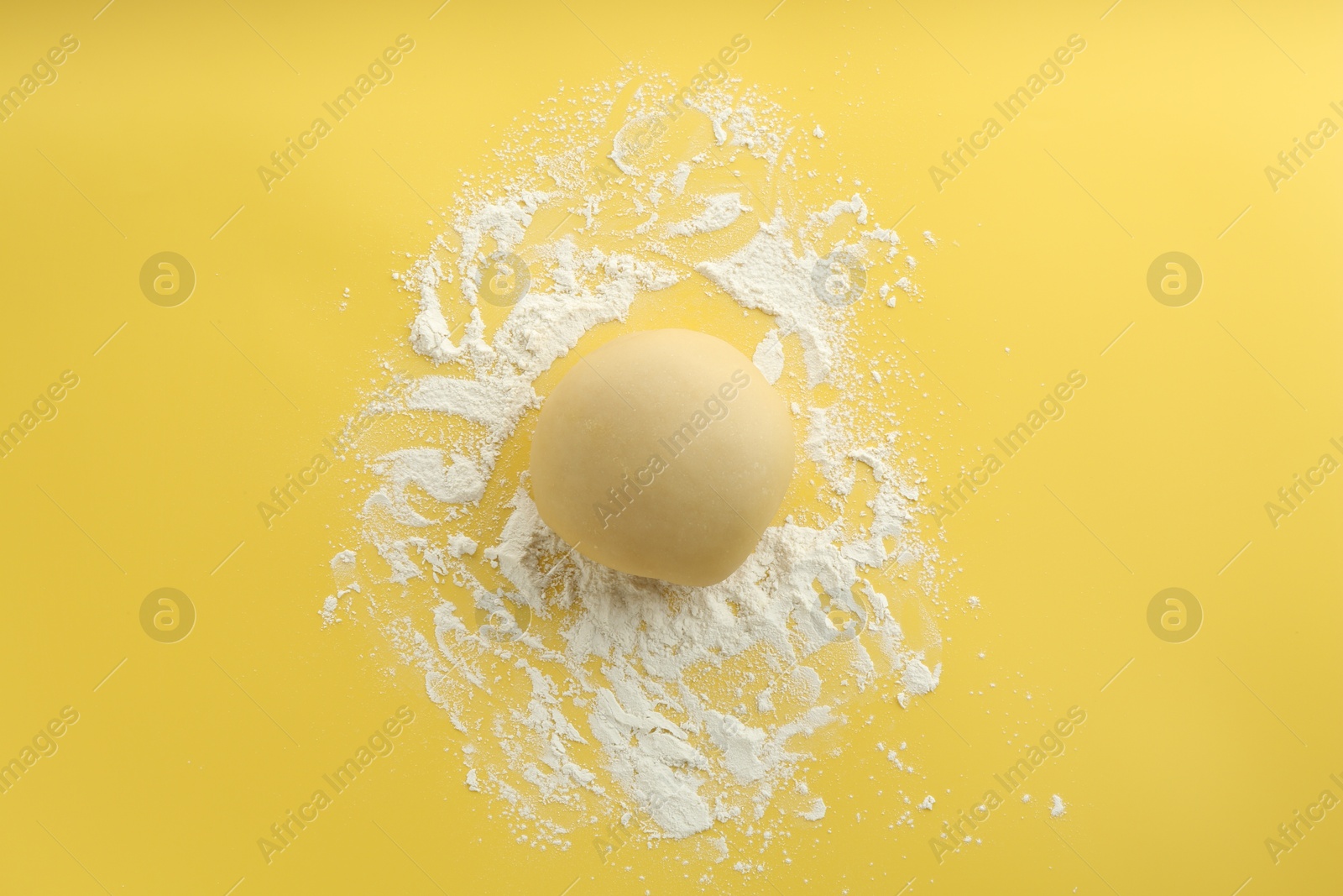 Photo of Cooking homemade pie. Raw dough and flour on yellow background, top view