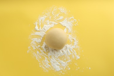 Photo of Cooking homemade pie. Raw dough and flour on yellow background, top view