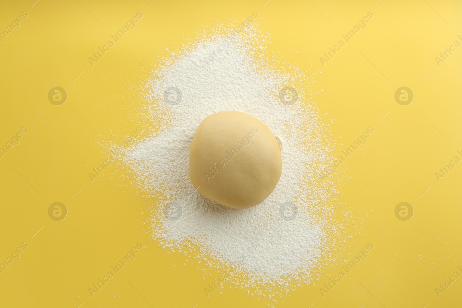 Photo of Cooking homemade pie. Raw dough and flour on yellow background, top view