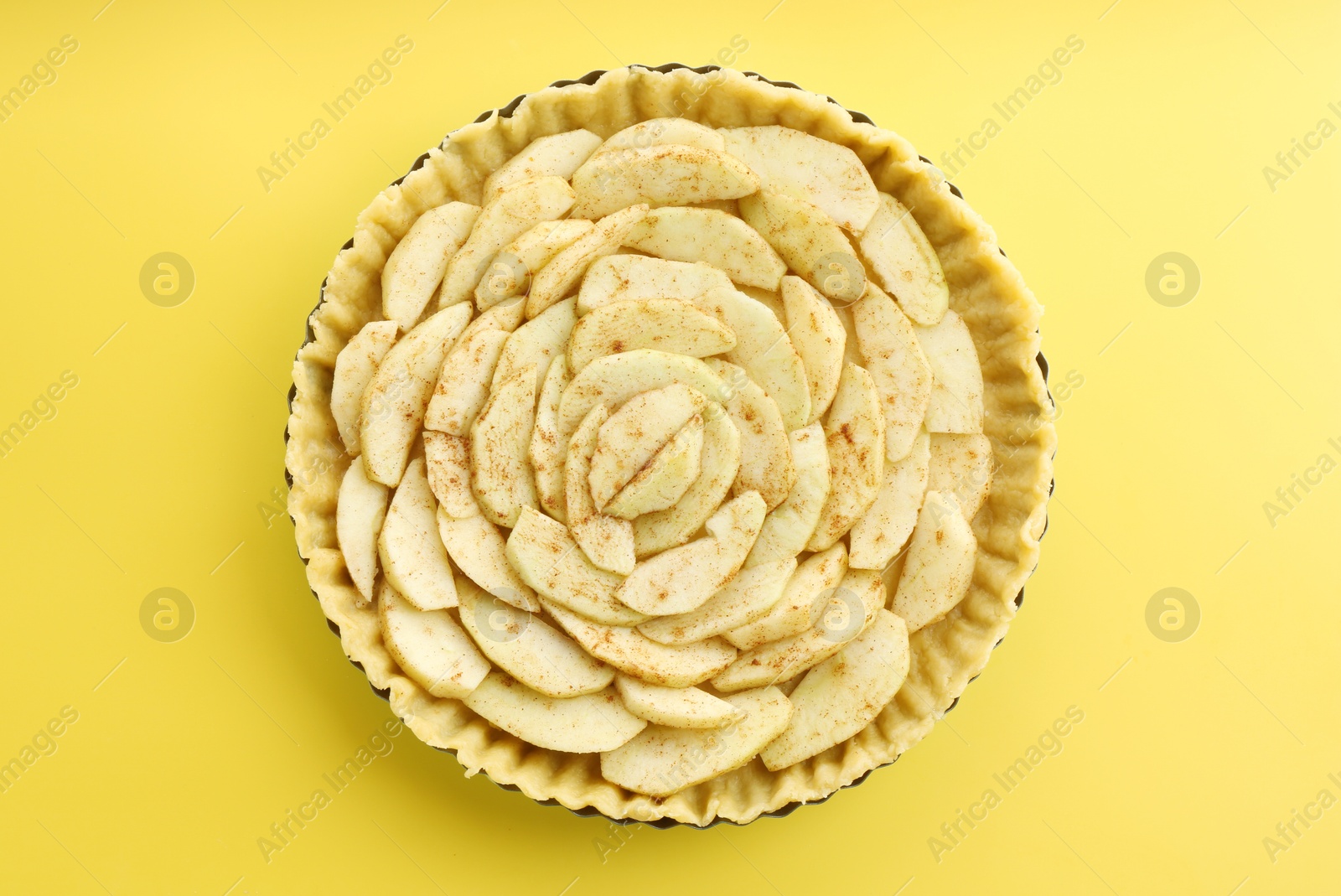 Photo of Raw homemade apple pie on yellow background, top view