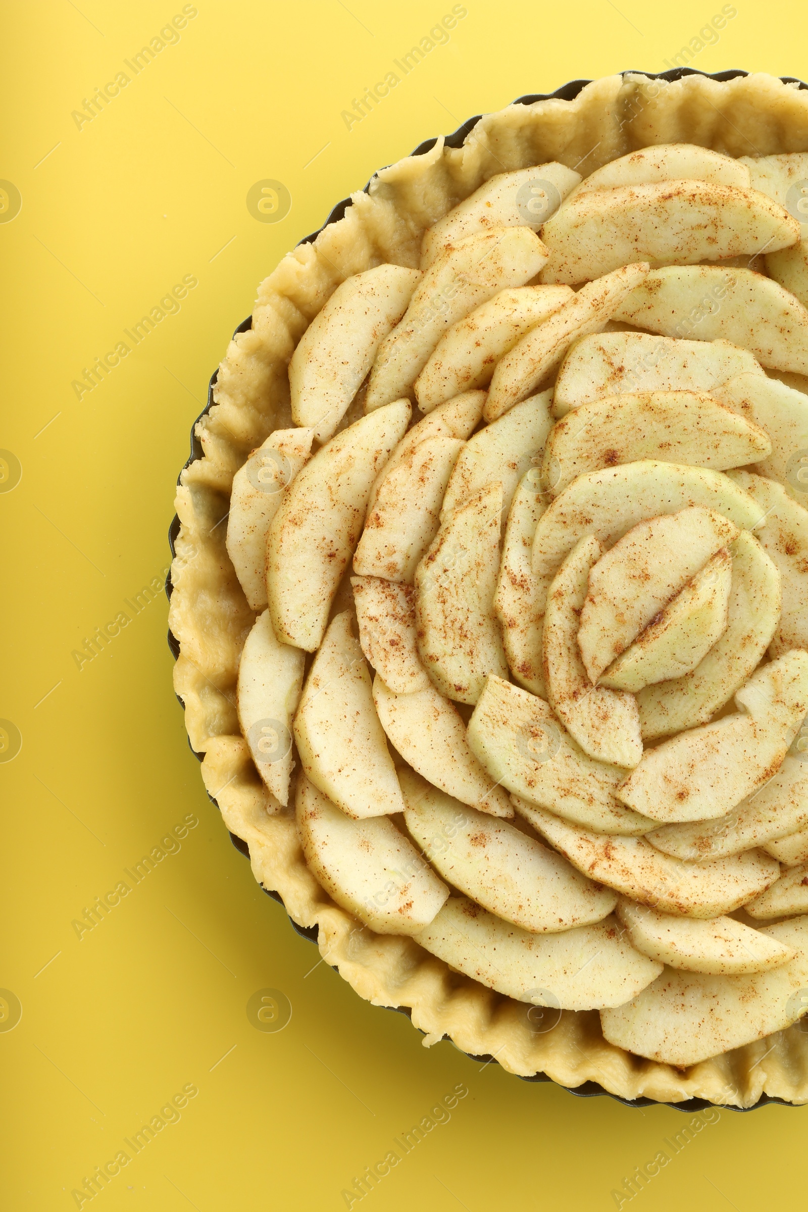 Photo of Raw homemade apple pie on yellow background, top view