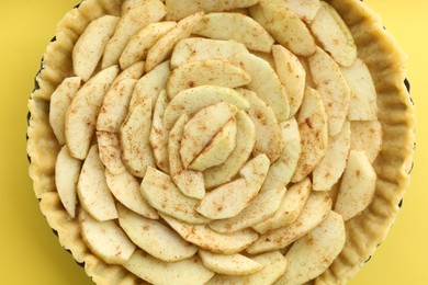 Photo of Raw homemade apple pie on yellow background, top view