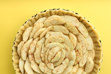 Photo of Raw homemade apple pie on yellow background, top view