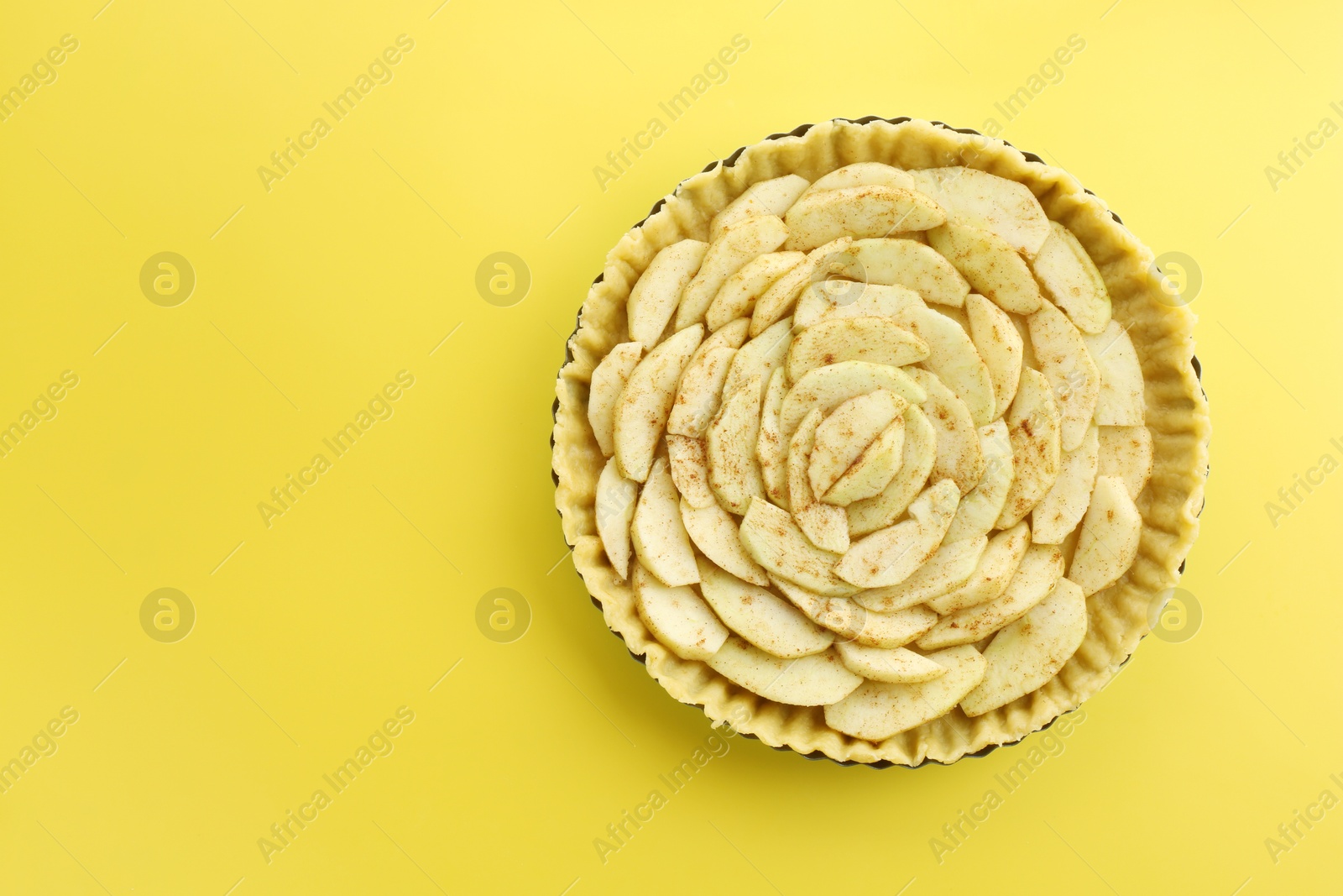 Photo of Raw homemade apple pie on yellow background, top view. Space for text