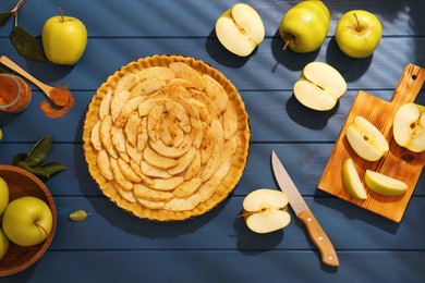 Uncooked homemade apple pie and ingredients on blue wooden table, flat lay