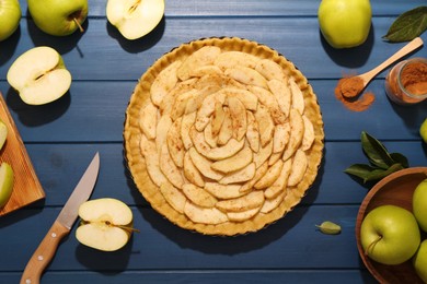 Photo of Uncooked homemade apple pie and ingredients on blue wooden table, flat lay