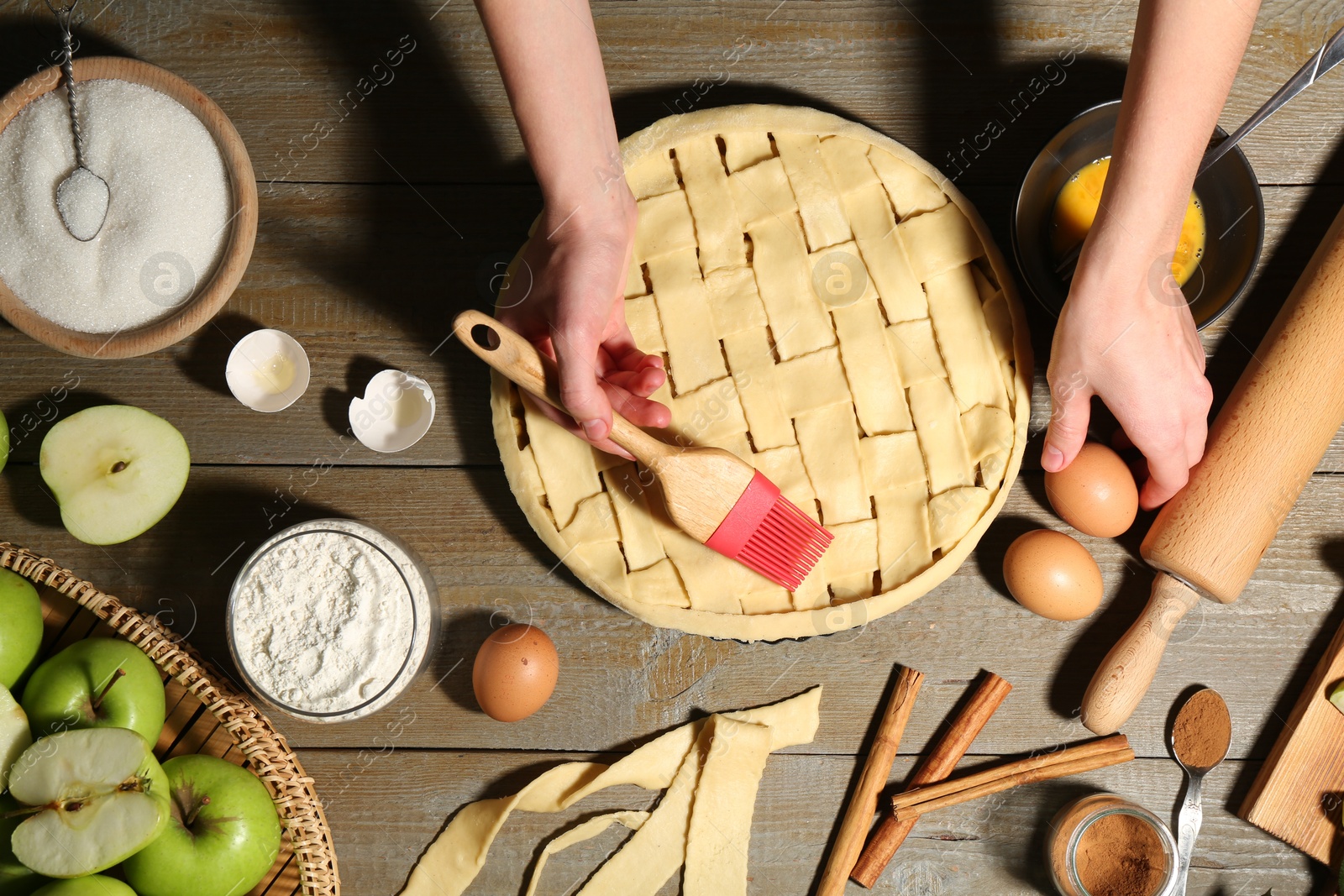 Photo of Woman making homemade apple pie and ingredients on wooden table, top view