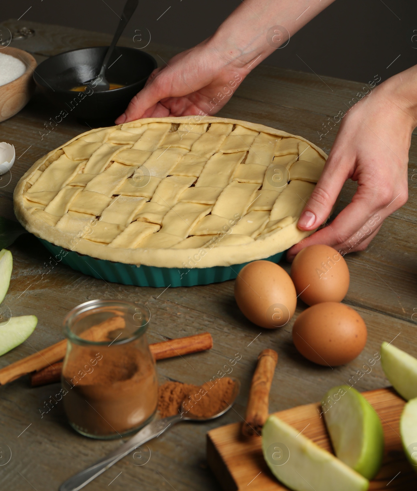 Photo of Woman making homemade apple pie and ingredients on wooden table, closeup