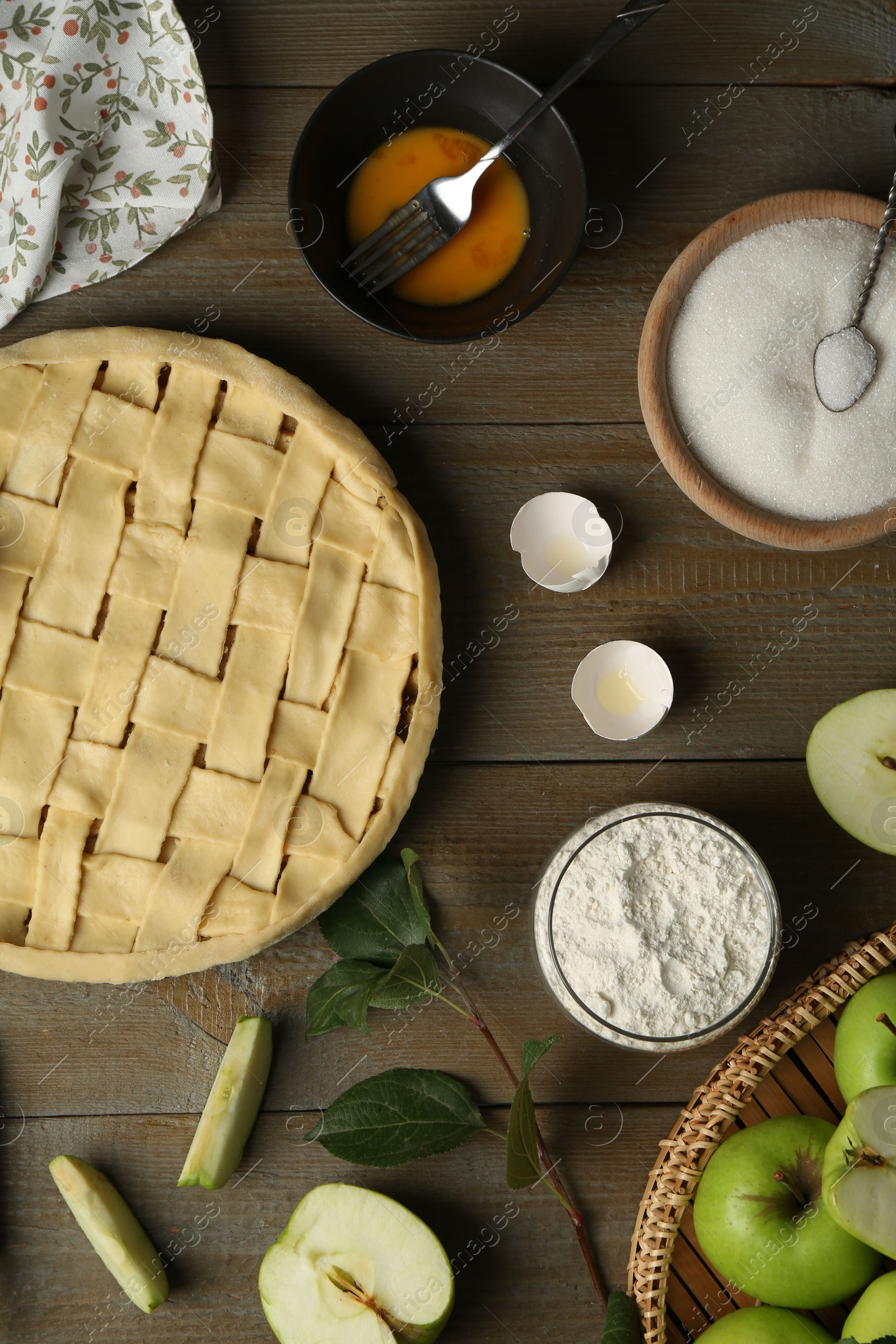 Photo of Uncooked homemade apple pie and ingredients on wooden table, flat lay