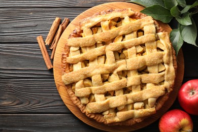 Photo of Tasty homemade apple pie and ingredients on wooden table, flat lay