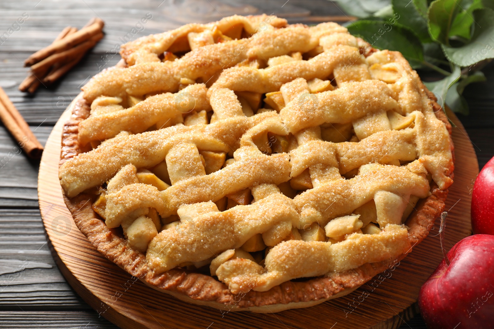 Photo of Tasty homemade apple pie and ingredients on wooden table, closeup