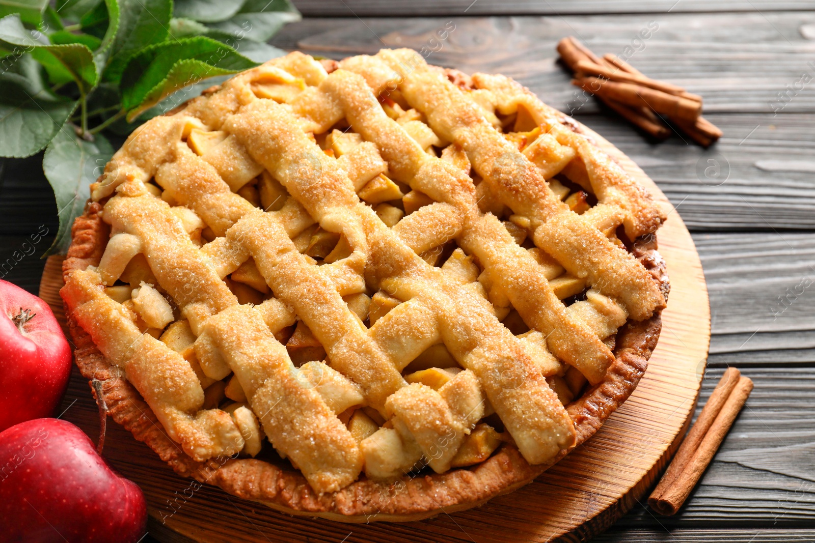 Photo of Tasty homemade apple pie and ingredients on wooden table, closeup