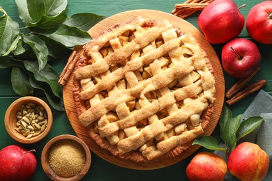 Photo of Tasty homemade apple pie and ingredients on green wooden table, flat lay