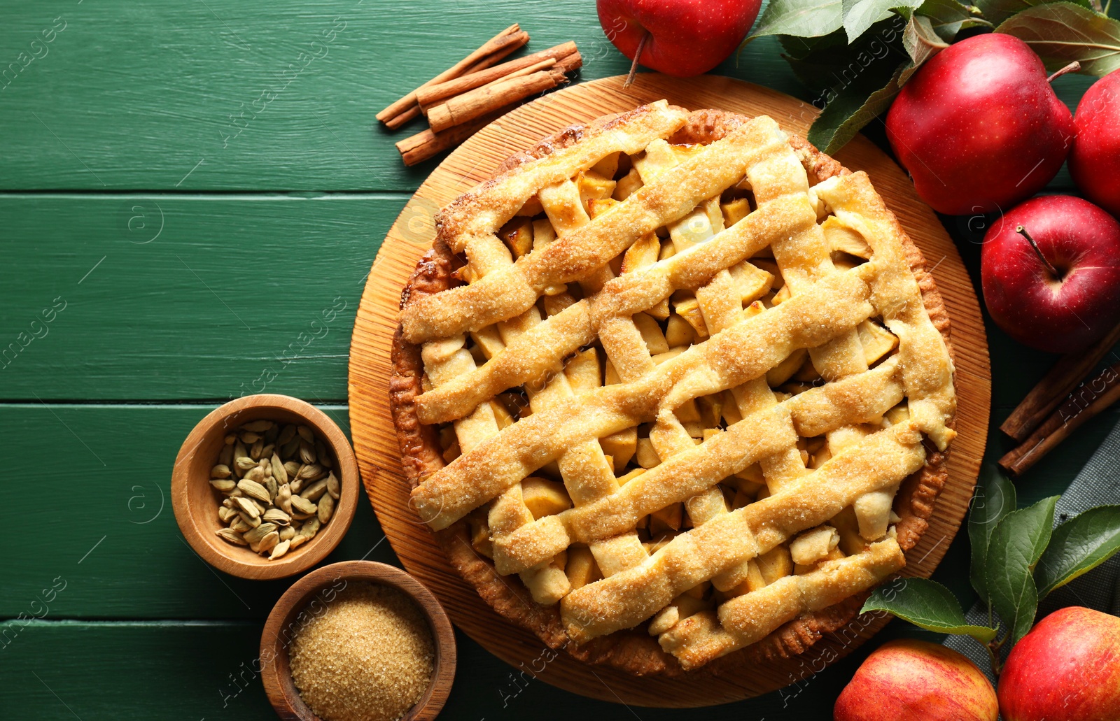 Photo of Tasty homemade apple pie and ingredients on green wooden table, flat lay