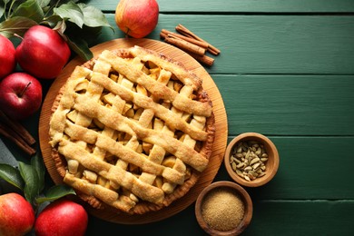 Photo of Tasty homemade apple pie and ingredients on green wooden table, flat lay