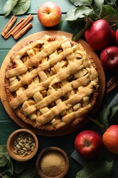 Photo of Tasty homemade apple pie and ingredients on green wooden table, flat lay