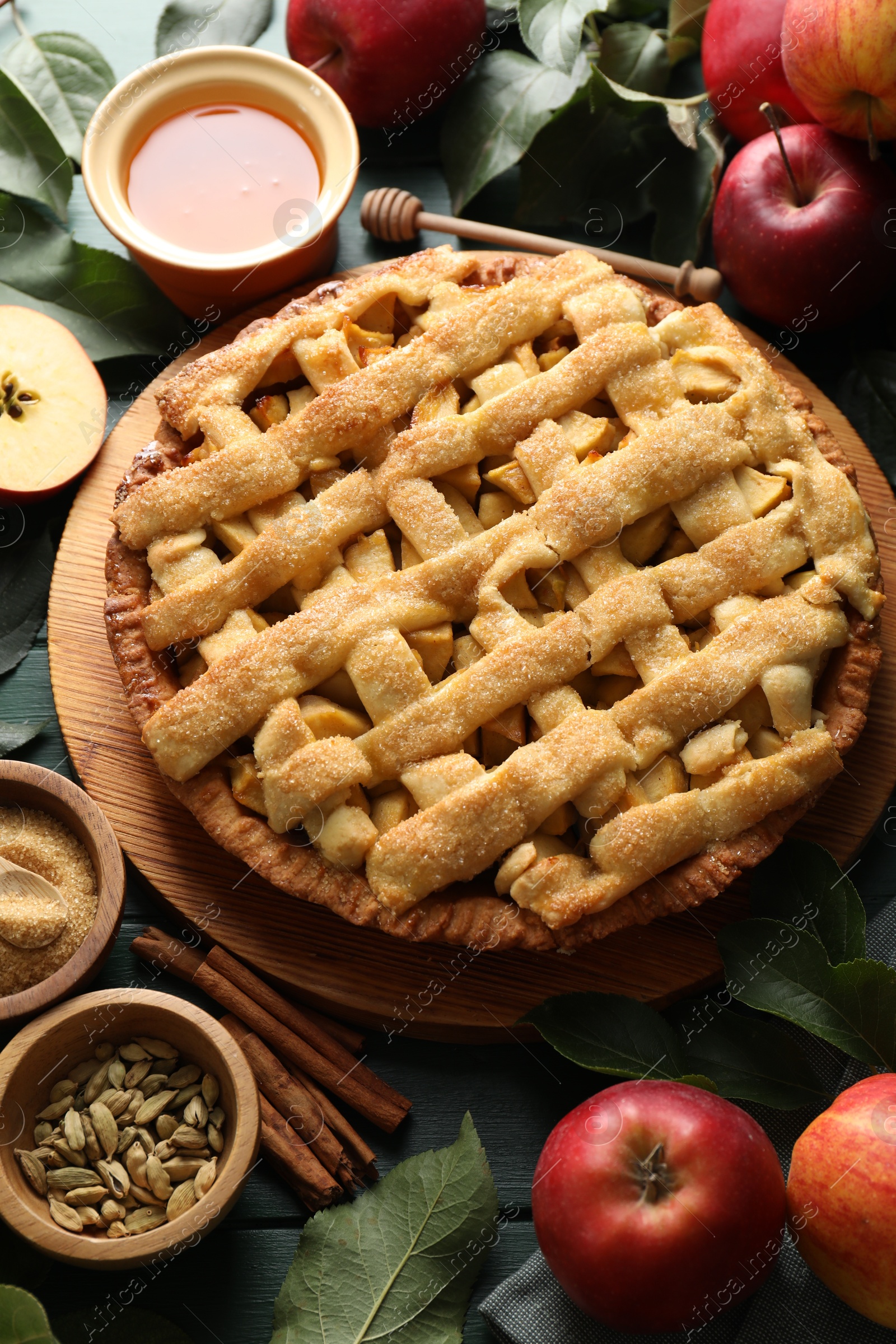 Photo of Tasty homemade apple pie and ingredients on green wooden table, above view