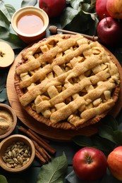 Tasty homemade apple pie and ingredients on green wooden table, above view