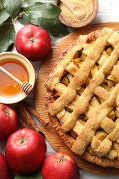 Tasty homemade apple pie and ingredients on white wooden table, flat lay