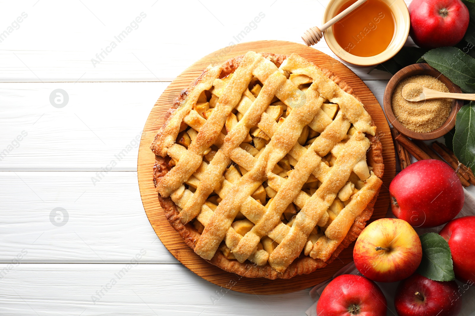 Photo of Tasty homemade apple pie and ingredients on white wooden table, flat lay. Space for text