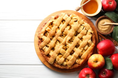 Tasty homemade apple pie and ingredients on white wooden table, flat lay. Space for text