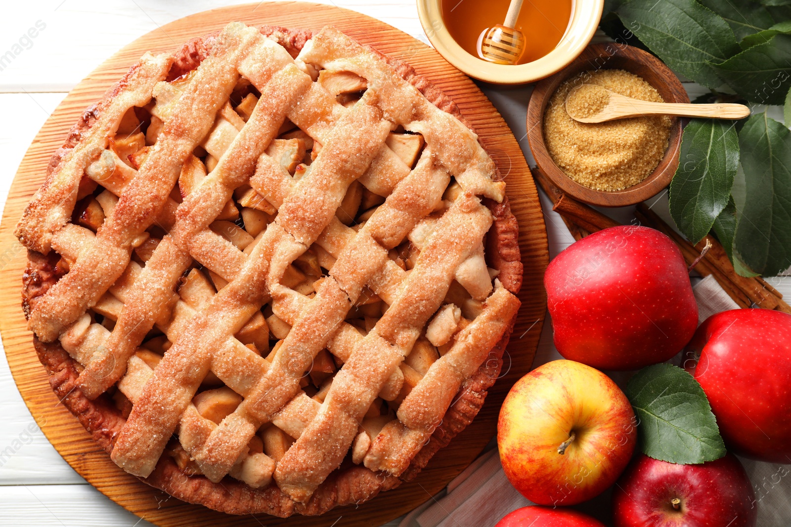 Photo of Tasty homemade apple pie and ingredients on white wooden table, flat lay