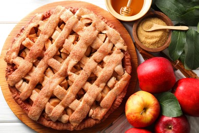 Tasty homemade apple pie and ingredients on white wooden table, flat lay