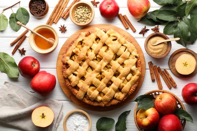 Tasty homemade apple pie and ingredients on white wooden table, flat lay