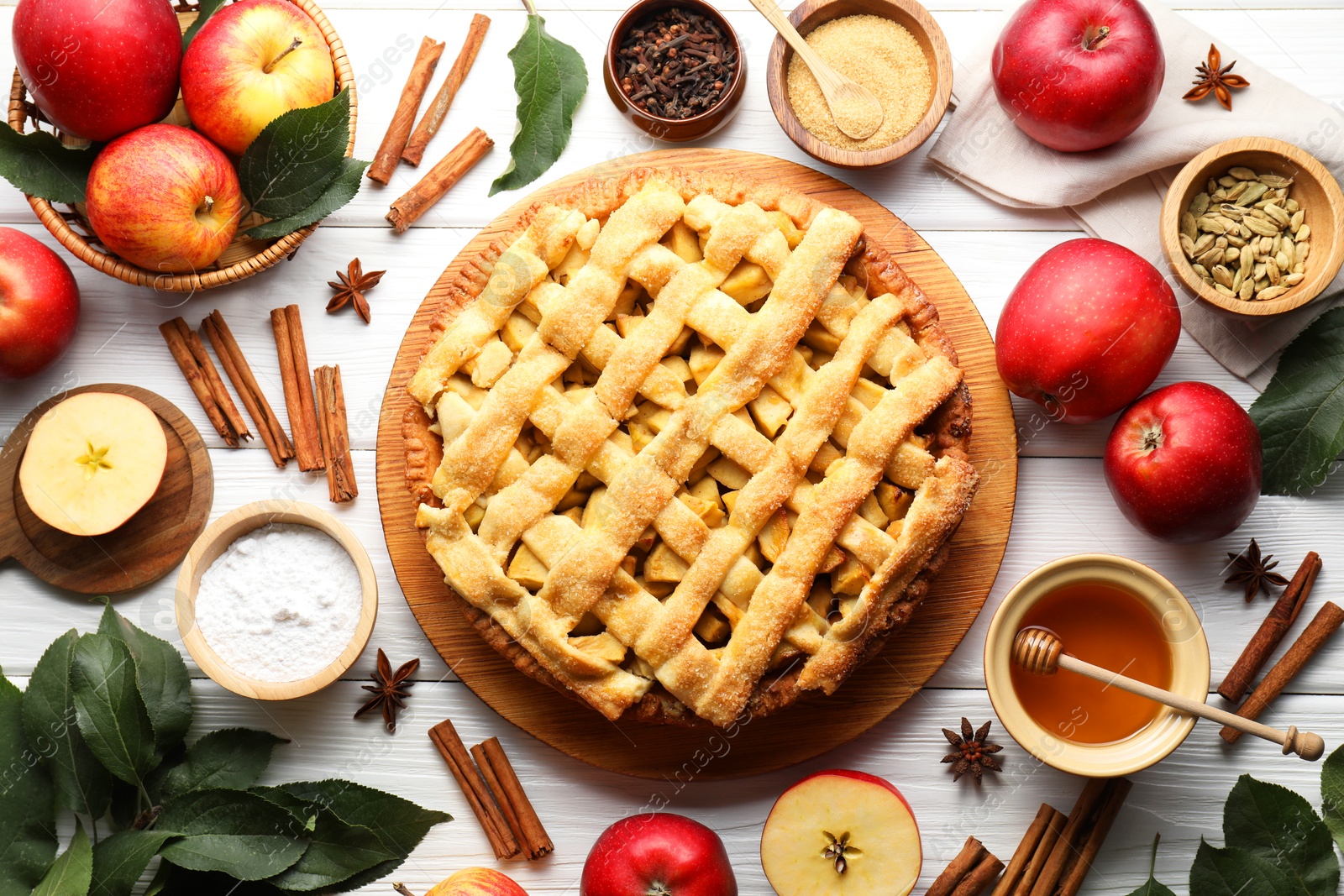 Photo of Tasty homemade apple pie and ingredients on white wooden table, flat lay