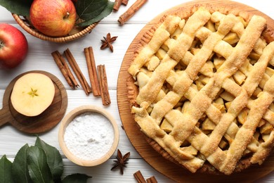 Photo of Tasty homemade apple pie and ingredients on white wooden table, flat lay