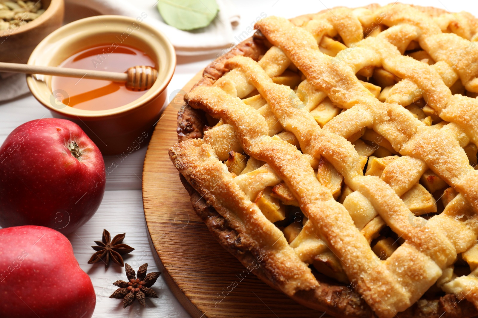 Photo of Tasty homemade apple pie and ingredients on white wooden table, closeup