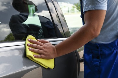 Man wiping car door with yellow rag, closeup